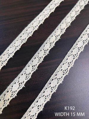 K192 15 mm greige dyeable cotton edging with repeating oval motifs and lattice detail