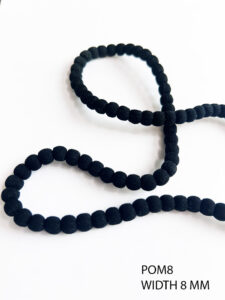 Close-up of POM 8 POM POM Soft Black Lace with pom pom detailing on soft net fabric